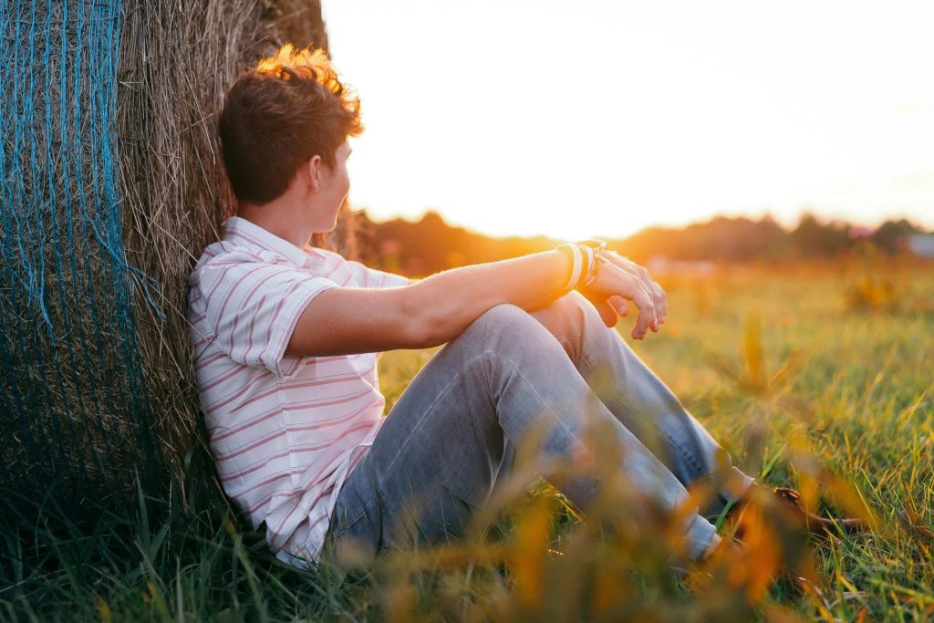 Jeune ado assis dans la nature face à l’horizon, illustrant une thérapie adolescent à Montpellier